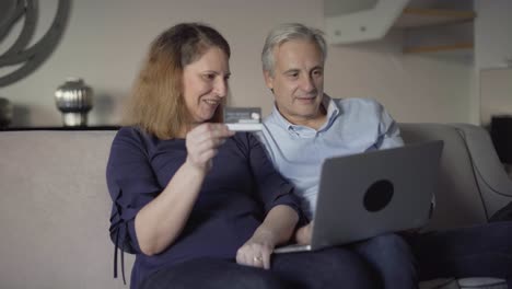 Positive-middle-aged-couple-purchasing-online-together